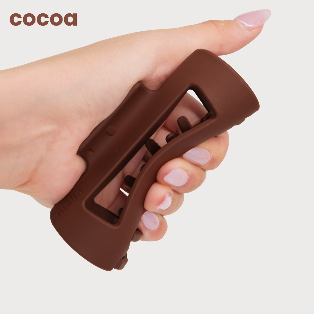 Hand holding a brown, silicone grip device.